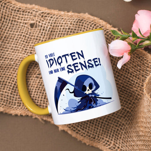 Kubek z nadrukiem i napisem w kolorze niebieskim - Tyle idiotów, a tylko jedna kosa
