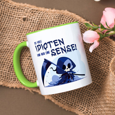 Kubek z nadrukiem i napisem w kolorze niebieskim - Tyle idiotów, a tylko jedna kosa