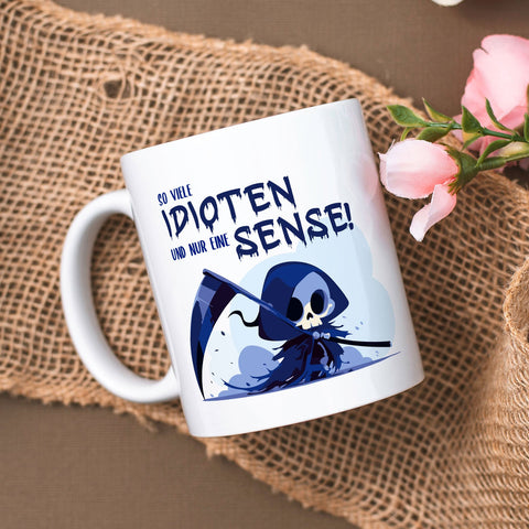 Kubek z nadrukiem i napisem w kolorze niebieskim - Tyle idiotów, a tylko jedna kosa